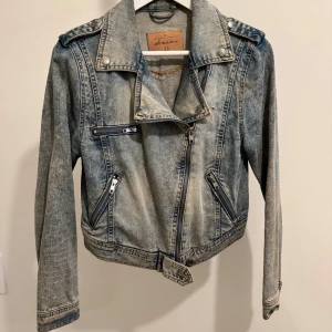 Jeansjacka melerad - Säljer en snygg jeansjacka i storlek 38. Jackan har en cool bikerstil med dragkedjor och knappar. Perfekt för vår och höst! Den är i mycket bra skick och har en klassisk blå denimfärg.