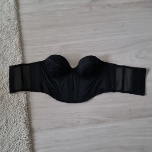 Korsett från hm helt ny - Det är en korsett i storlek 75A, från H&M helt ny köpte för 3 dagar sen. [Den är inte använd!.] den är i helt nytt skick. Den har som bh knappar där back den är helt blank svart med lite nät i bak i ryggens slut den är inte så lång den är till typ.