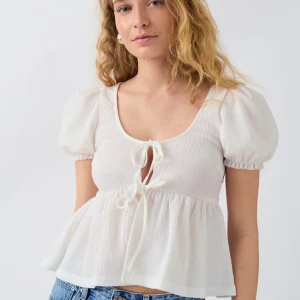 Vit blus med knytning - Säljer en superfin vit blus från Monki. Den har korta puffärmar och en söt knytning framtill. Perfekt för vår och sommar! Blusen är i ett lätt och luftigt material, vilket gör den bekväm att bära hela dagen. Helt oanvänd med lappar kvar!