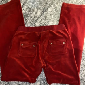 Röda juciy couture byxor - Säljer mina röda juciy pga att jag inte använder. Dom är i bra skick skulle jag säga det ändå är ju typ att metallsaken på ena snöret sitter lite löst💗 köparen står för frakt💗