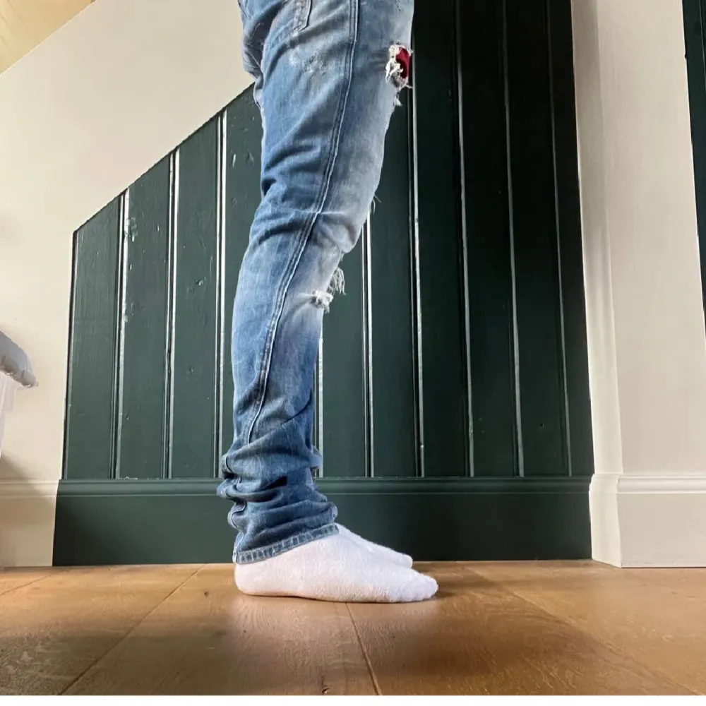 Säljer ett par blå jeans med slitningar och hål för en cool och avslappnad look. De har en slim passform och är perfekta för vardagsbruk. Jeansen har en klassisk femficksdesign och är tillverkade i denim. Perfekta för både höst och vår!. Jeans & Byxor.