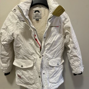Mysig Parkas vinter jacka  från Didriksons stl 140 - Säljer en superfin vit vinterjacka från Didriksons i storlek 140.Knappt använd. Jackan har en mysig fleecefodring och praktiska fickor med knappar.  Den har en avtagbar huva och stängs med dragkedja och knappar. 