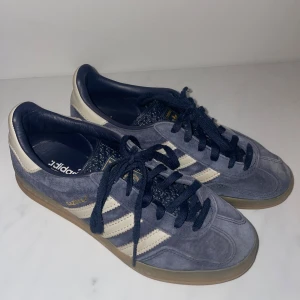 Adidas Gazelle i blå mocka - Säljer ett par Adidas Gazelle i blå mocka med vita detaljer. Skorna har endast blivit använd ca 5 gånger och då varsamt. Perfekta för både vardag och festliga tillfällen.🩷🩷