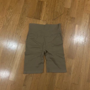 Beige ribbade shorts från New Apparel - Säljer ett par bekväma mörkbeige shorts i cykelbyxformat från New Apparel i storlek M. De är ribbade och har en hög midja för en skön passform. 