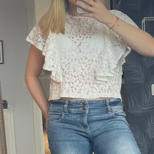 Vit spetsblus med volanger - Säljer en superfin vit spetsblus med volangdetaljer. Perfekt för sommardagar eller en festlig kväll. Blusen har korta ärmar och en luftig passform. Den är i mycket bra skick och passar perfekt till jeans eller kjol. Endast använd 1-2 gånger. :)