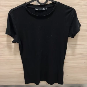 Svart tight t-shirt från 157 - Säljer en tight svart t-shirt från 157 i storlek M. Den är kortärmad och har en klassisk rund halsringning. Har använts som sovtröja så kan vara lite nopprig