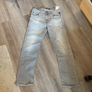 Grå jeans från Replay - Säljer ett par grå jeans från Replay i bra skick, men med en liten reva vid benet. De har en straight/ Loose fit passform och är perfekta för vardagsbruk. Jeansen har klassisk design med fem fickor och knappgylf. Perfekta för höst och vår!