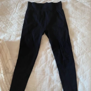 Svarta ribbade leggings från H&M Sport - Säljer ett par svarta ribbade leggings från H&M Sport i storlek M. De är superbekväma med hög midja och perfekt för träning. Säljer då de är lite förstora för mig.