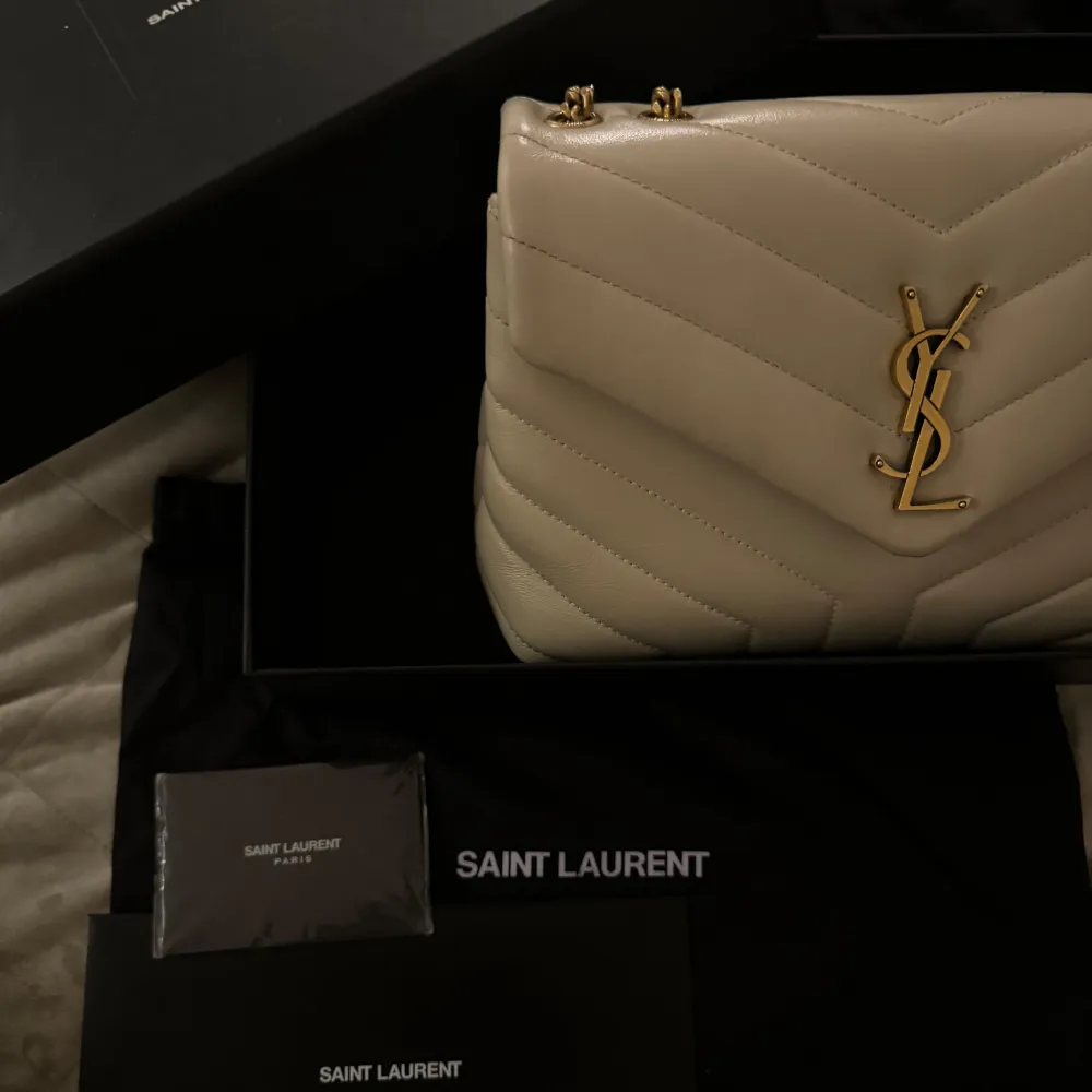 Säljer denna Yves Saint Laurent väska i beige, i lilla Loulou modellen. Väskan är i princip i nytt skick alltså använd endast ett fåtal gånger. Nypris är cirka               27 200kr. Box, dustbag, kvitto, äktenhets certifikat medföljer. Väskan är även beställd ifrån deras hemsida. . Väskor.