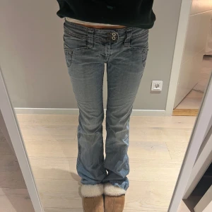 Ljusblå lågmidjade bootcut jeans - Säljer ett par ljusblå bootcut jeans i bra skick. De är lågmidjade med två knappar och dragkedja fram. Så himla snygg tvätt!!