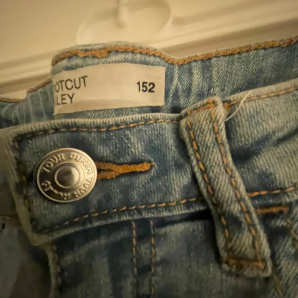 Säljer ett par ljusblå bootcut jeans i storlek 152. De har en cool slitning på knäna och en klassisk femficksdesign. Perfekta för en avslappnad stil med en touch av edge. Passar bra till både vardag och fest!. Jeans & Byxor.