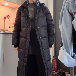 Dunkappa - Jättebra skick nästan inte använd alls! Dunjackan är inte riktigt min stil men den är väldigt lång, lätt och varm. Bra vinterjacka! Har huva. Kan knäppa upp längst ner för mer rörlighet. 