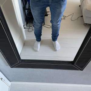 Säljer ett par snygga blå jeans i slim fit. De har en klassisk femficksdesign och är perfekta för vardagsbruk. Jeansen är i bra skick och har en bekväm passform. 30/30