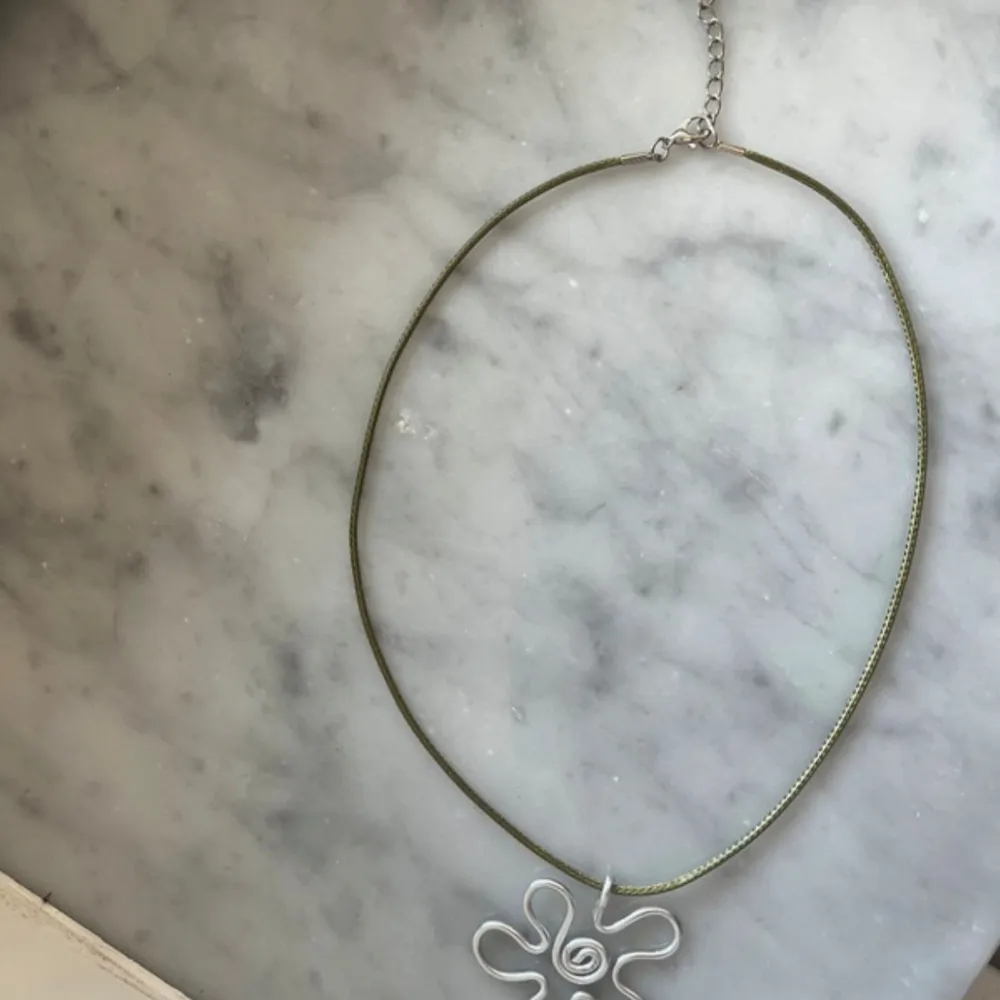 Egengjort halsband med berlock silvrig blomma gjort i aluminiumtråd, med mörkgrönt läderband/snöre, justerbart! Skriv för frågor och skicka prisförslag <3. Accessoarer.