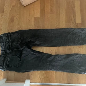 Svarta jeansbyxor - Säljer ett par svarta jeansbyxor i storlek 36. De har en klassisk design med fem fickor och knappgylf. Perfekta för vardagsbruk och kan enkelt matchas med olika outfits.