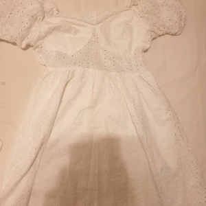 Vit klänning - Vit klänning med puffärmar och spetsdetaljer. Klänningen är figursydd och har en elastisk midja.Super fin använd endast en gång 80kr