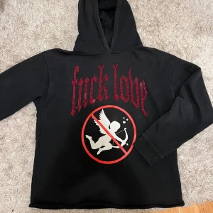 fuck love hoodie  - Cool svart hoodie med ett iögonfallande tryck i rött och vitt. Texten 'fuck love' är dekorerad med röda stenar och en grafisk bild av en ängel med ett förbudstecken. Perfekt för en edgy stil. condition 10 of 10 