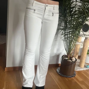Vita bootcut byxor med dragkedjor och nitar  - Snygga vita bootcut byxor från micheal kors med dragkedjor framtill och nitar på bakfickorna. Utsydda till bootcut. Strl 4 midjemått 37 cm grenmått 20 cm innerbenslängd 76 cm