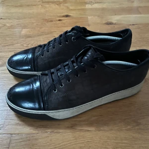 Lanvin - Snygga svarta  lanvins med snörning och en vit sula. Skorna har en stilren design med en glansig captoe och snyggt krokodilskinn. Perfekta för en utekväll! Storlek 45 och relativt bra skick