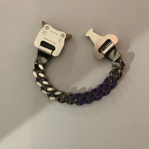 Silver och lila armband från 1017 ALYX 9SM - Snyggt armband från 1017 ALYX 9SM med en unik kombination av silver och lila länkar. Armbandet har en modern design med ett robust spänne som ger en cool och stilren look. Nypris ca 2000-3500kr