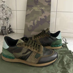 Valentino Rockrunner i kamouflage - Snygga Valentino Rockrunner sneakers i kamouflage med gröna och bruna nyanser. Skorna har en unik design med snörning och detaljer i mocka och syntetmaterial. Perfekta nu till vinter! Kvitto från illum finns och självklart följer allt if med :) 