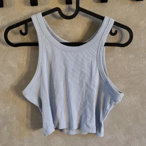 Ljusblå ribbad linnetopp från 157 - Säljer en ljusblå ribbad linnetopp från 157. Toppen är ärmlös och croppad, perfekt för varma dagar. Den har en enkel och stilren design som passar till många olika outfits.
