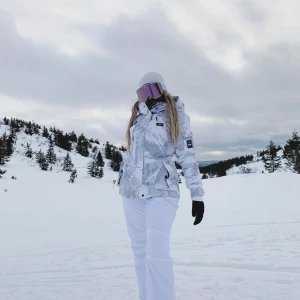 Vit och grå camouflage Snowboardjacka - Snygg vit och grå camouflage vinterjacka med dragkedja och knappar. Jackan har en hög krage och flera praktiska fickor. Perfekt för kalla dagar i skidbacken. Passar Xs-S, priss kan diskuteras 