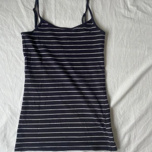 Striped åtsittande topp i fint skick - Säljer ett stilrent randigt linne från Atmosphere. Den är mörkblå med vita ränder och har smala axelband. Perfekt till vardag