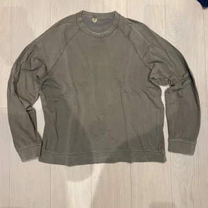 Arket sweatshirt - Säljer en stilren grön sweatshirt från Arket med rund hals och långa ärmar. Perfekt för en avslappnad look. Ser snyggt washed ut. Ett väldigt svagt cirkulärt märke i första bilden som är näst intill osynligt när man hat på sig tröjan