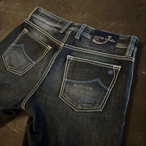 Mörkblå jeans från Jacob Cohën - Snygga mörkblå jeans från Jacob Cohën med klassisk femficksdesign och kontrastsömmar. Jeansen har är tillverkade i högkvalitativt denim. Perfekta för en stilren look. Modellen är slim limited edition!