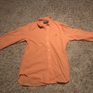 Ralph lauren skjorta - Snygg orange rutig skjorta från Polo Ralph Lauren i slim fit. Skjortan har långa ärmar och knappar framtill. Perfekt för en stilren look.