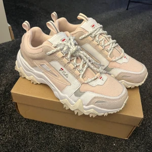 Beige sneakers från Fila - Säljer dessa superfina, helt nya fila sneakers! Aldrig använda, bara testade. Inga defekter eller fläckar. Med tanke pa att de är i helt nyskick kommer jag inte gà ner i pris fa Nypris 800kr Storlek 39