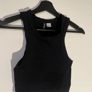 Svart ribbad linnetopp - Snygg svart ribbad linnetopp från H&M Perfekt för en stilren look, med en croppad passform och breda axelband. Ett mångsidigt plagg för olika tillfällen.