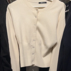 Vit kofta från Gina Tricot - Säljer en stilren vit kofta från Gina Tricot med rund halsringning och knappar framtill. Perfekt för lager-på-lager och passar till många olika outfits.