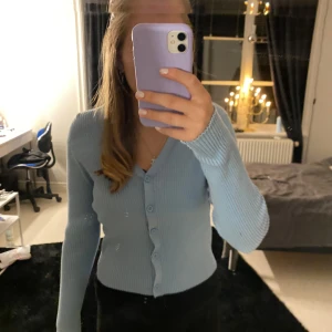 Gullig kofta - Säljer en ljusblå ribbad kofta från Sincerely Loved. Koftan har en v-ringad design med knappar framtill och långa ärmar. Perfekt för en stilren och bekväm look.