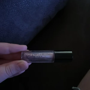 Transparent läppglans med glitter - Säljer ett transparent läppglans med glittereffekt. Perfekt för att ge läpparna en glansig och skimrande look. Kommer i en smidig tub med svart lock.