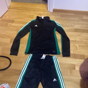 Svart och grön sett från Adidas - Snyggt träningsset från Adidas i svart med gröna och vita detaljer. Helt ny med prislappen kvar, säljer dom då en familjemedlem inte ville behålla settet. Pris går att diskutera☺️