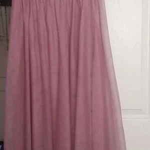 Rosa långklänning med paljettdetaljer - Elegant rosa långklänning med vackra paljettdetaljer och broderade bladmotiv. Klänningen har en satinliknande midja och ett luftigt fall. Perfekt för speciella tillfällen.