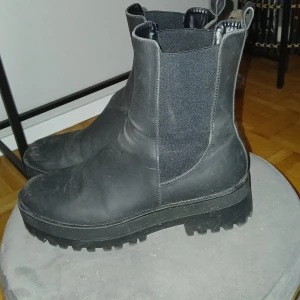 Svarta chelsea boots - Snygga svarta chelsea boots med grov sula och elastiska paneler på sidorna för enkel på- och avtagning. Perfekta för en stilren look. Passar både till fest och vardags.