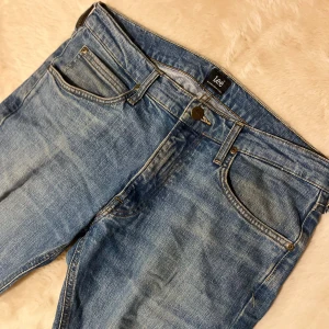 Blå jeans från Lee - Snygga blå jeans från Lee i modellen Luke. De har en klassisk femficksdesign med dragkedja och knapp. Perfekta för en avslappnad stil. W: 32 L: 32