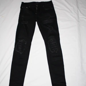 Faygo Jeans  - Svarta faygo jeans med slitningar. Storlek: midja ca 39cm, längd ca 105cm.