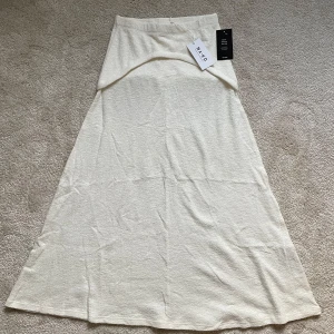 Vit långkjol från NA-KD M  - Elegant vit långkjol från NA-KD i ett mjukt och bekvämt material. Perfekt för en stilren look. Kjolen har en enkel design som gör den lätt att matcha med olika toppar.