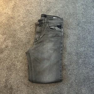 Grå jeans från Replay - Snygga grå jeans från Replay med klassisk femficksdesign. De har en diskret tvättad look och en bekväm passform. Perfekta för en stilren. Skriv till mig om ni undrar något eller har någon fråga. Pris går att diskutera! MVH Jacob