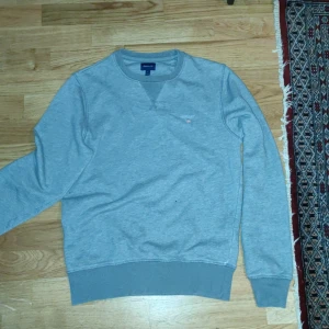 Grå sweatshirt från Gant - Säljer en stilren grå sweatshirt från Gant. Tröjan har en rund halsringning och långa ärmar med ribbade muddar. Perfekt för en avslappnad stil. Superbra skick i stl S