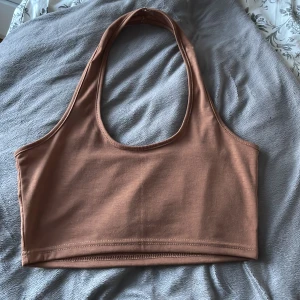 Brun halterneck topp - Säljer en brun halterneck topp. Toppen har en enkel design med rund halsringning 🌟