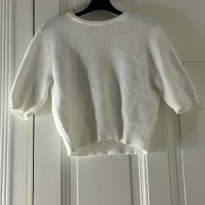 Vit stickad tröja från Zara - Säljer en stilren vit stickad tröja från Zara med trekvartsärm. Tröjan har en rund halsringning och är tillverkad i ett mjukt material som ger en bekväm passform. Perfekt för en minimalistisk look. (Aldrig använt)