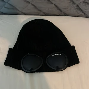 Svart mössa från C.P. Company - Snygg svart mössa från C.P.  Perfekt för att hålla stilen och värmen under kyliga dagar.