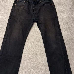 Svarta Levi's 501 jeans - Snygga svarta Levi's 501 jeans med klassisk design. De har en rak passform och är tillverkade i slitstarkt denim. Perfekta för en stilren look.