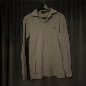 Grå pikétröja från Ralph Lauren - Säljer en stilren grå pikétröja från Ralph Lauren i custom fit. Tröjan är i mycket bra skick och har inte defekter. Kontakta gärna vid frågor☺️