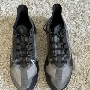 Grå och svarta Nike air zoom - Snygga grå och svarta Nike sneakers med snörning och en modern design. Perfekta för både träning och vardag. Skorna har en stilren look med Nike-loggan på sidan. Pris kan diskuteras 